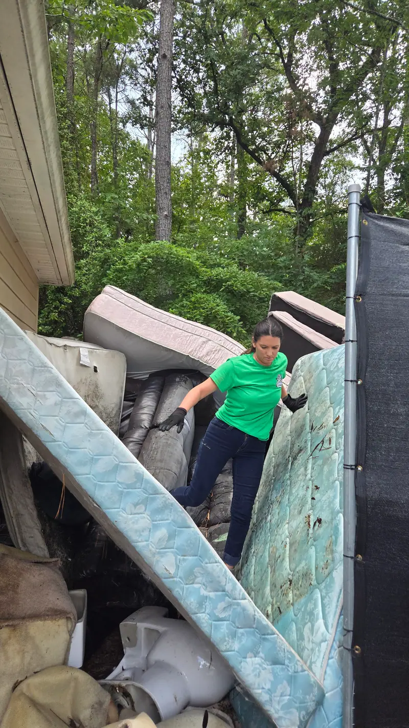 A crew member loading old mattresses into the trailer