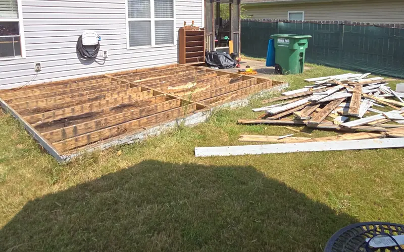 A deck mid-removal, the boards stacked on the lawn