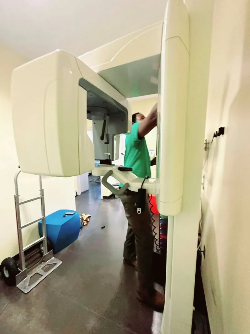 A crew member in a green Racoons shirt dismantling a dental imaging unit