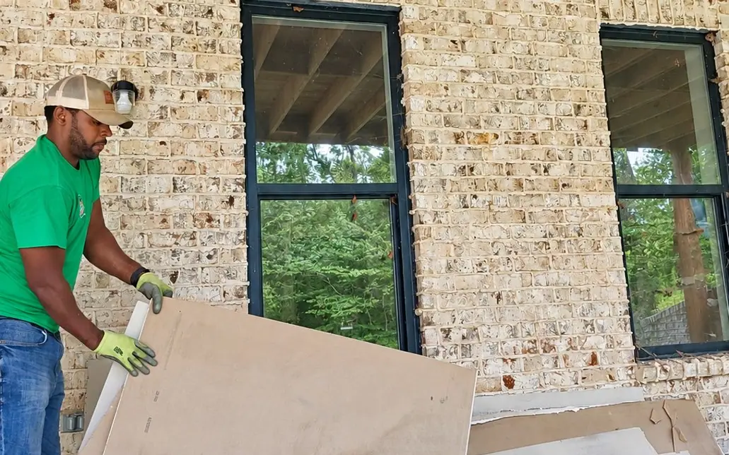 A Racoons crew member in a green shirt hauling drywall scraps off a new brick build