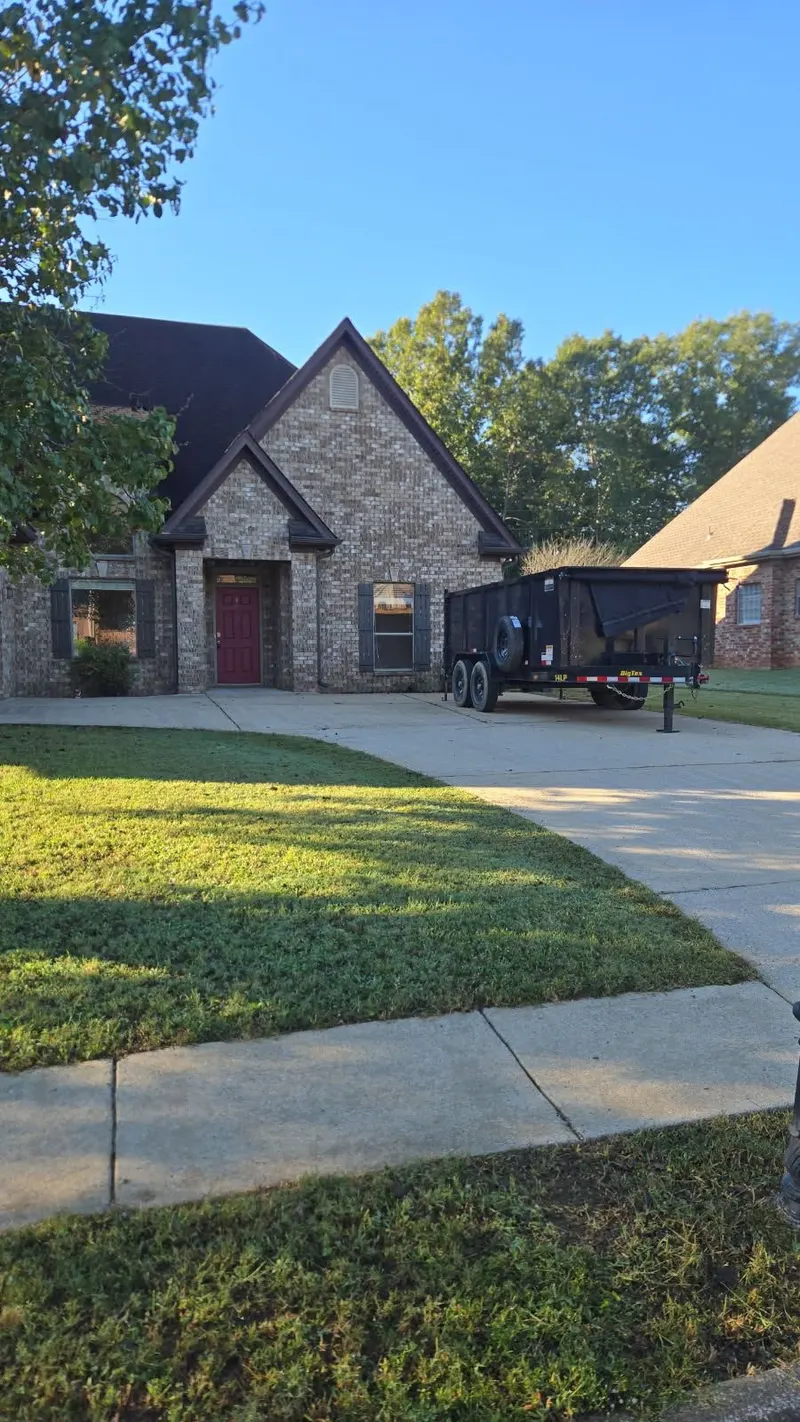 A Racoons dump trailer parked in the driveway of a brick home