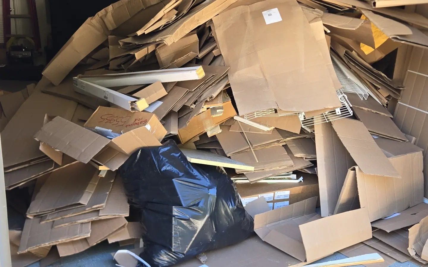A garage piled with flattened cardboard and bags before a Racoons garage cleanout