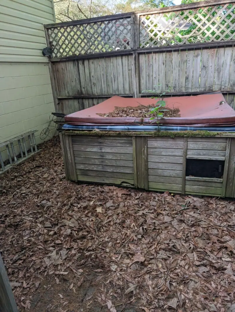 An old hot tub under a layer of leaves, waiting for removal