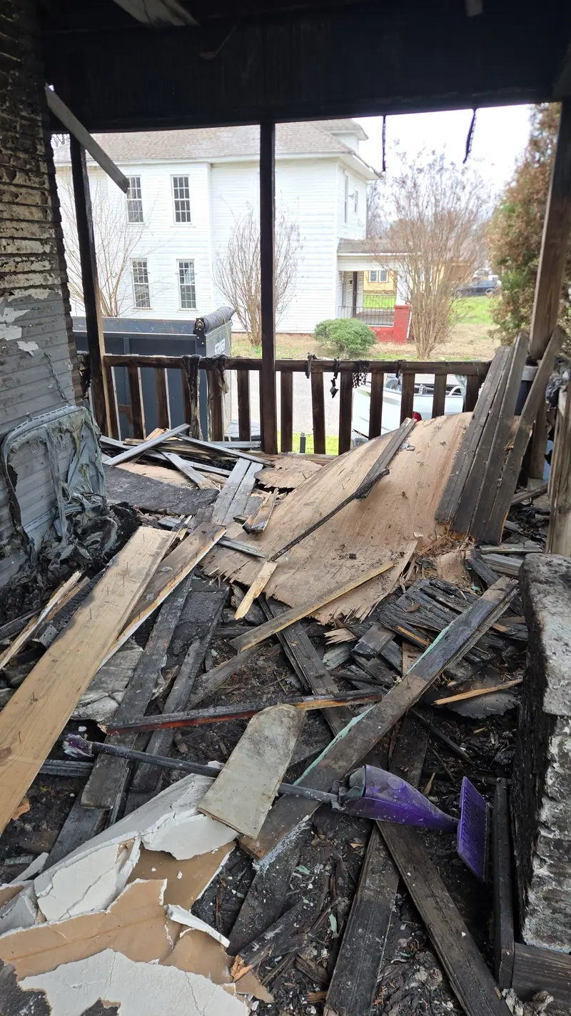 A fire-damaged porch buried in charred boards and debris