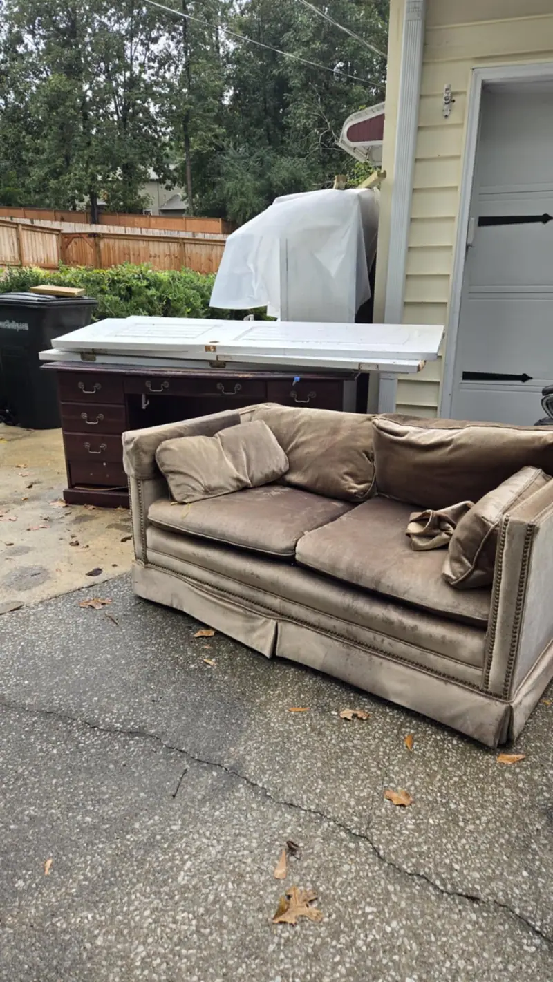 An old sofa and desk on a driveway, ready for pickup