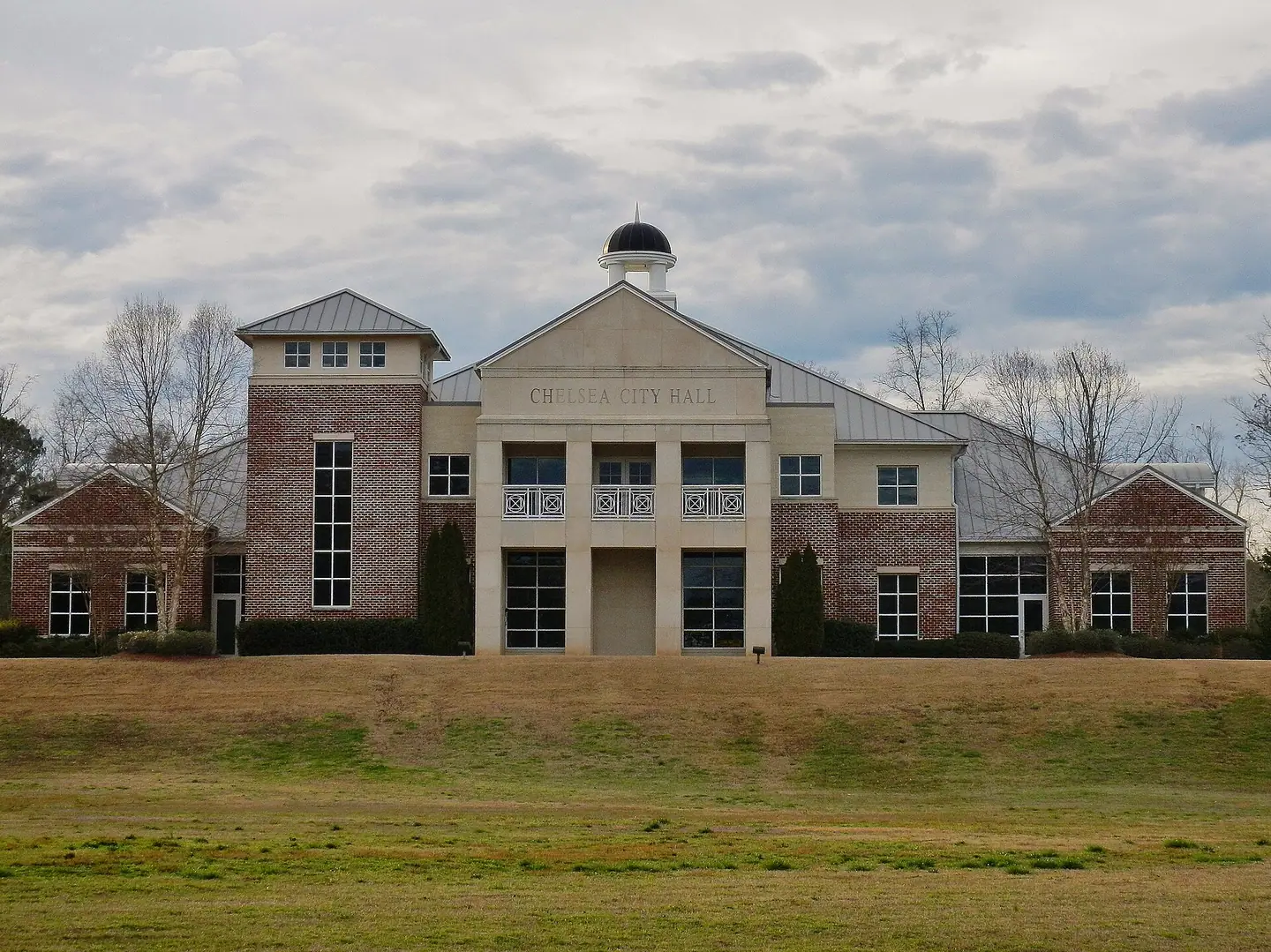 Chelsea City Hall, a brick and cream building with a small cupola behind a wide lawn