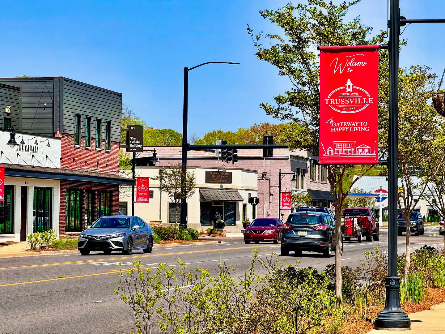 Brick storefronts and a "Welcome to Downtown Trussville" banner on a sunny street